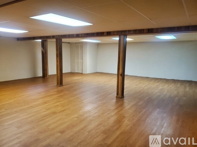 A spacious room with wooden floors and white walls.