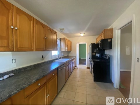 A kitchen with wooden cabinets and a black fridge.