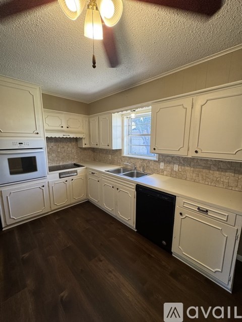 A kitchen with white cabinets and a black dishwasher.