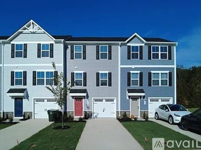 A row of townhouses with garages and a car parked in front.