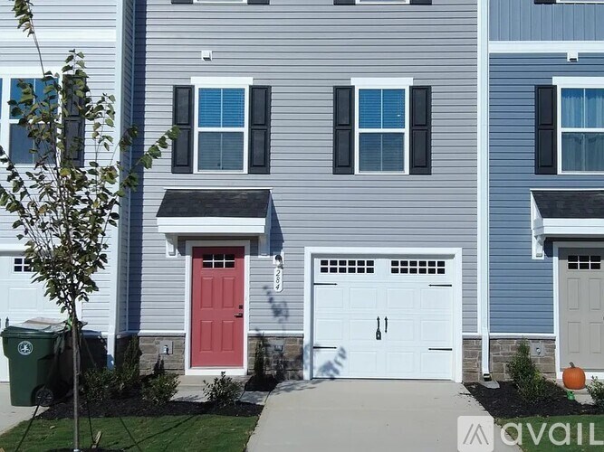 A two-story house with a red front door and white garage doors.