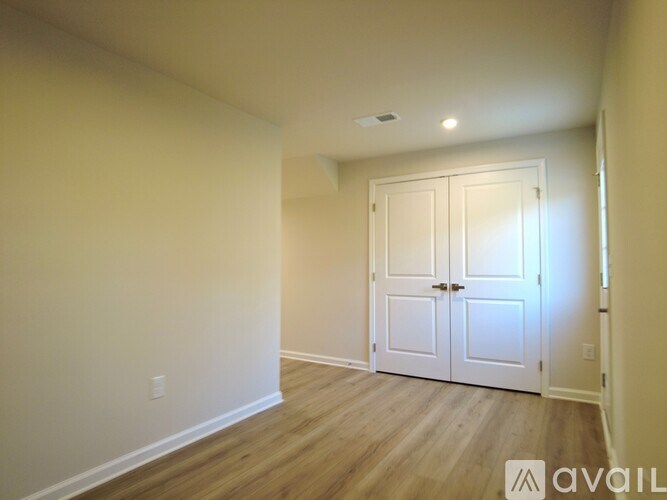 A room with a white door and wooden flooring.