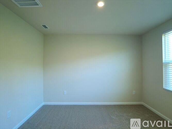 A room with a carpeted floor and a window with blinds.