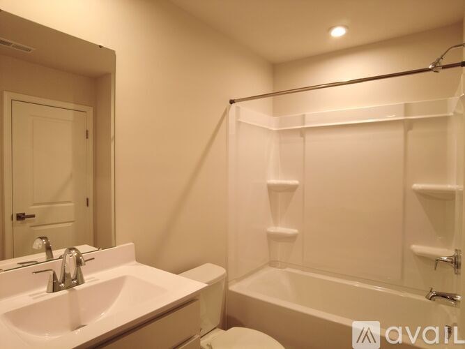 A white bathroom with a sink, mirror, and bathtub.