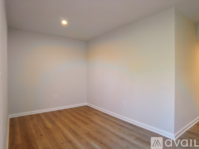 A room with wooden flooring and white walls.