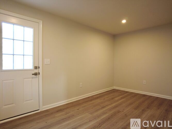 A room with a white door and wooden flooring.