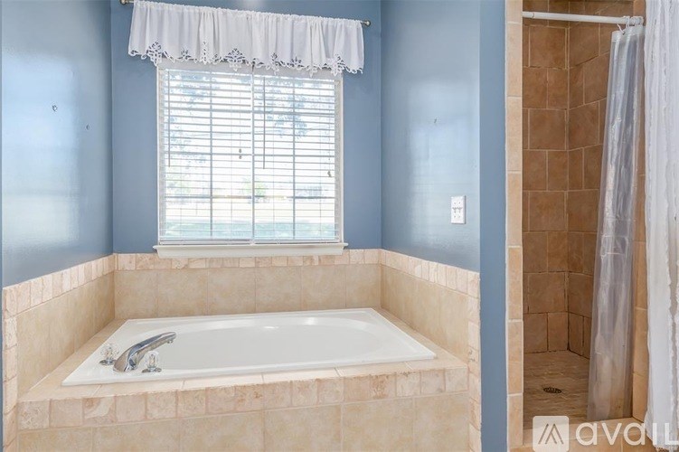 A bathroom with a tub and a window with blinds.