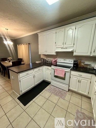 A kitchen with white cabinets and black countertops.