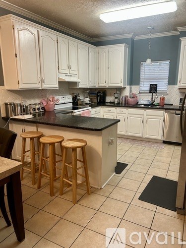 A kitchen with white cabinets and a black countertop.