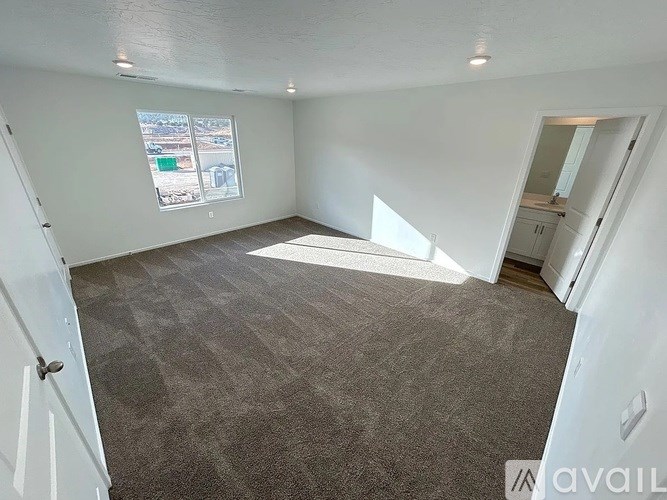A room with carpeted floor and a window showing a parking lot outside.