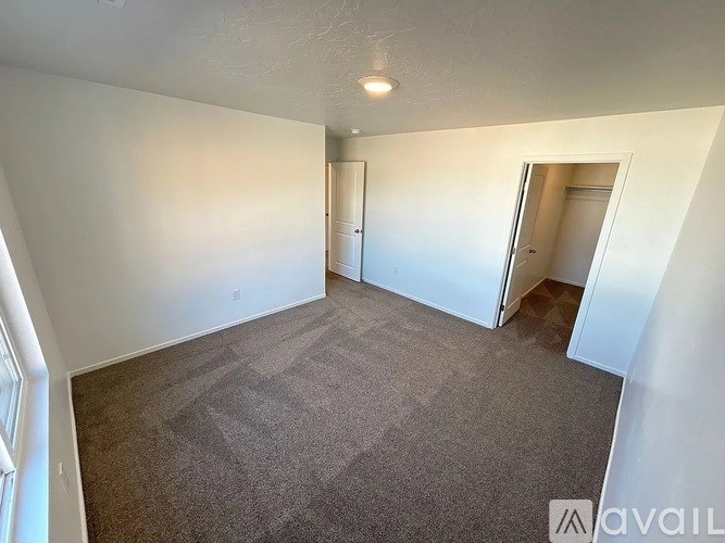 A room with carpeted floor and white walls, with a door on the right side.