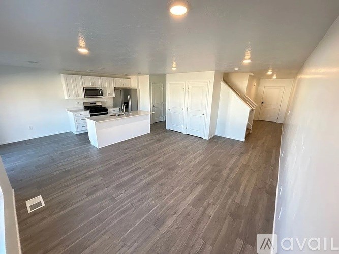 A spacious room with wooden flooring and white walls.