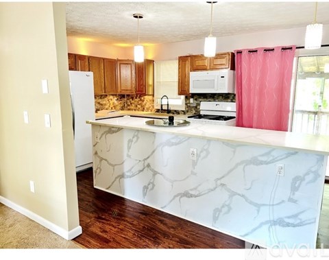 A kitchen with a marble counter top and wooden cabinets.