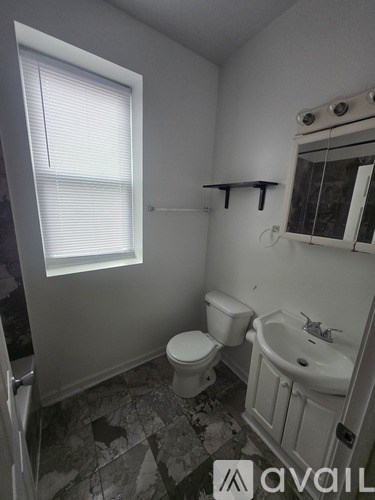 A bathroom with a toilet, sink, and window.