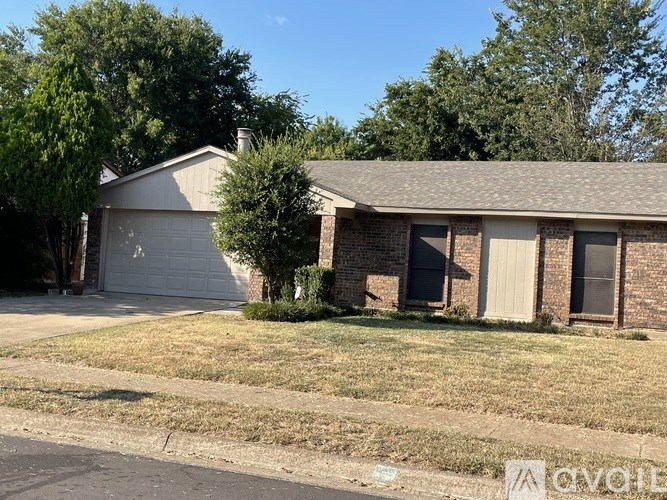 A house with a garage and a tree in front.