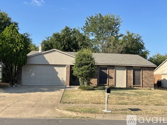 A house with a garage and a tree in front.