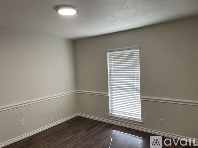 A room with a window covered by white blinds.