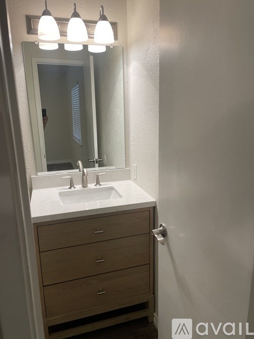 A bathroom with a sink, mirror and lighting.