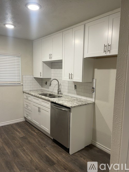 A kitchen with white cabinets and a granite countertop.