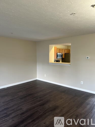 A room with wooden floors and a small kitchenette in the corner.