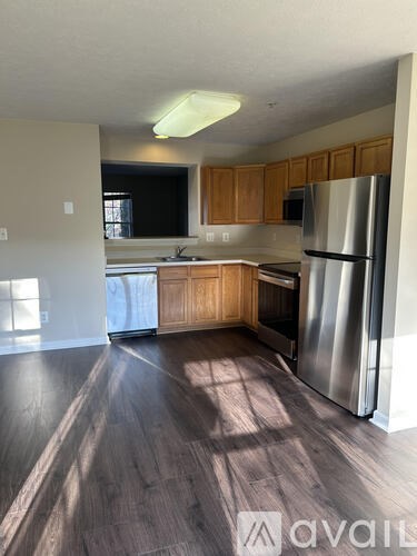 A kitchen with wooden cabinets and a stainless steel refrigerator.
