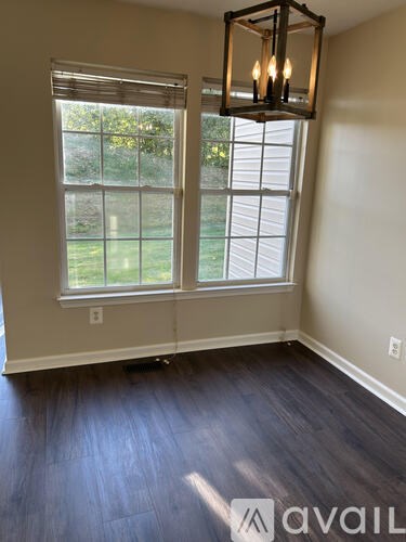A room with a large window and a hanging light fixture.