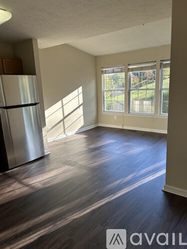 A kitchen with a stainless steel refrigerator and wooden flooring.