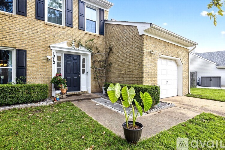 A house with a black door and windows has a small garden in front.