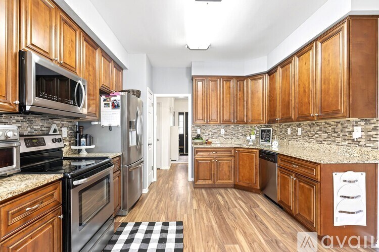 A kitchen with wooden cabinets and a black and white checkered mat on the floor.