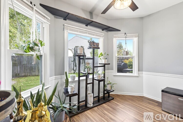 A room with a window, a fan, and a shelf with plants on it.