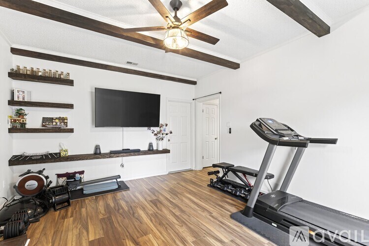 A home gym with a treadmill, weights, and a flat screen TV.