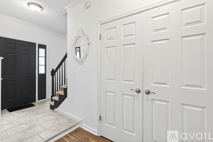 A hallway with white doors and a black door on the left.