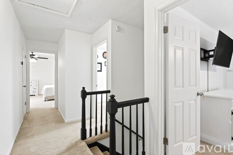 A hallway with a black railing and white walls.