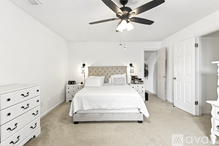 A bedroom with a bed, dresser, and ceiling fan.
