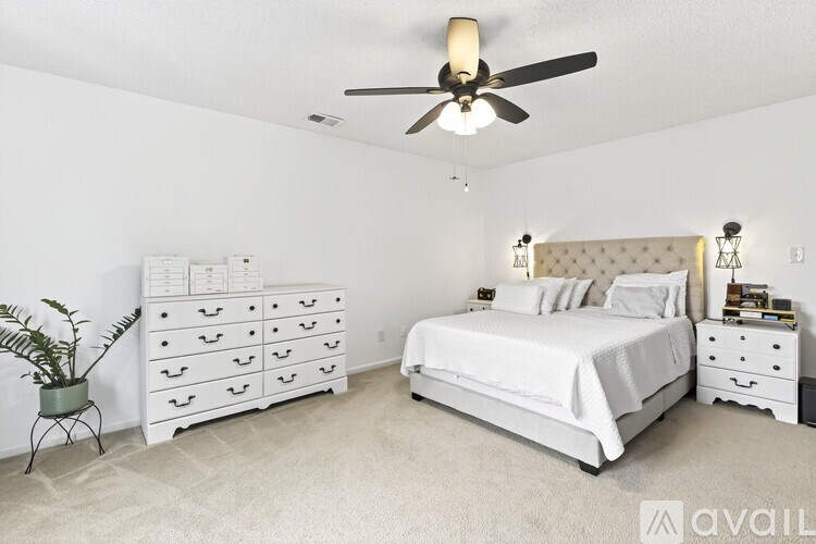 A white bedroom with a bed, dresser, and nightstand.