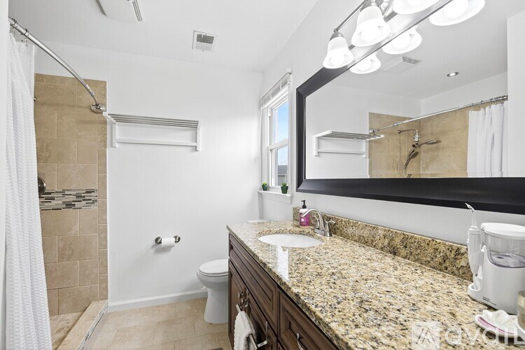 A bathroom with a marble countertop and a large mirror.