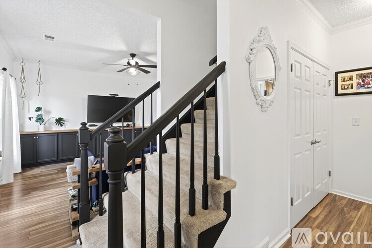 A staircase with a beige carpeted runner and black balusters leads to the second floor.