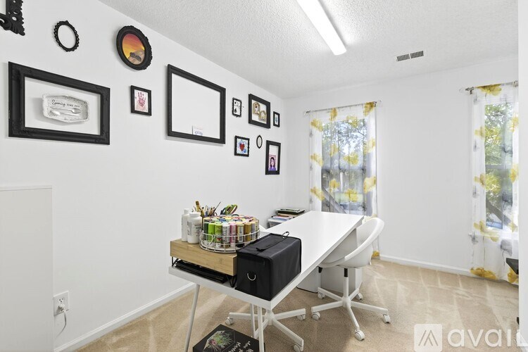A room with a desk, chair, and pictures on the wall.
