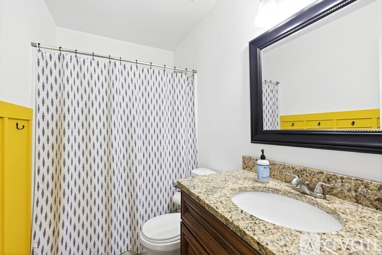 A bathroom with a yellow door, a sink, a toilet, and a shower curtain.