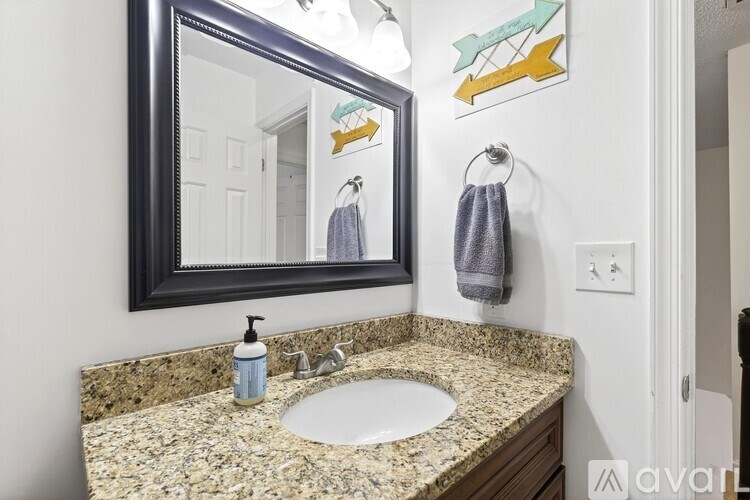 A bathroom with a sink, mirror, and towel.