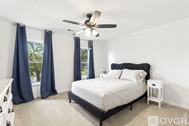 A bedroom with a bed, nightstand, and window with curtains.