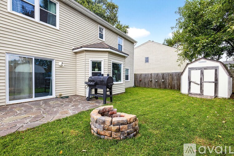 A backyard with a stone fire pit and a small shed.