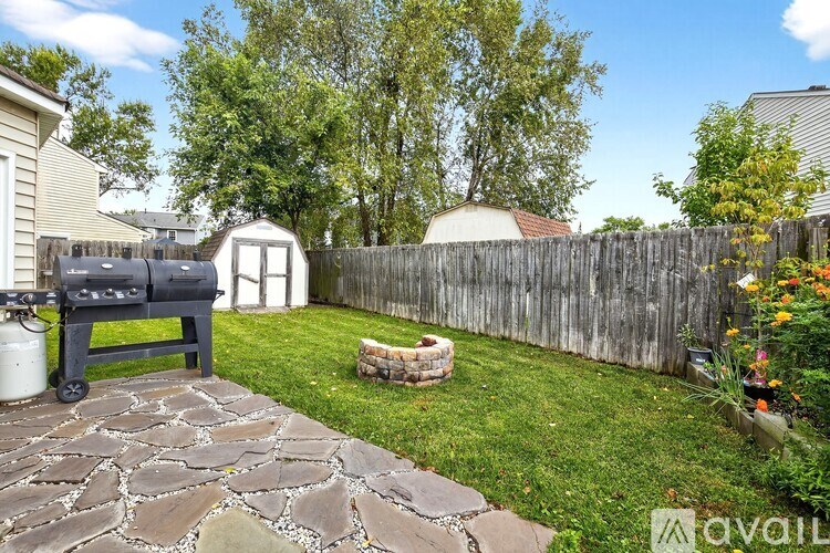 A backyard with a stone patio and a wooden fence.