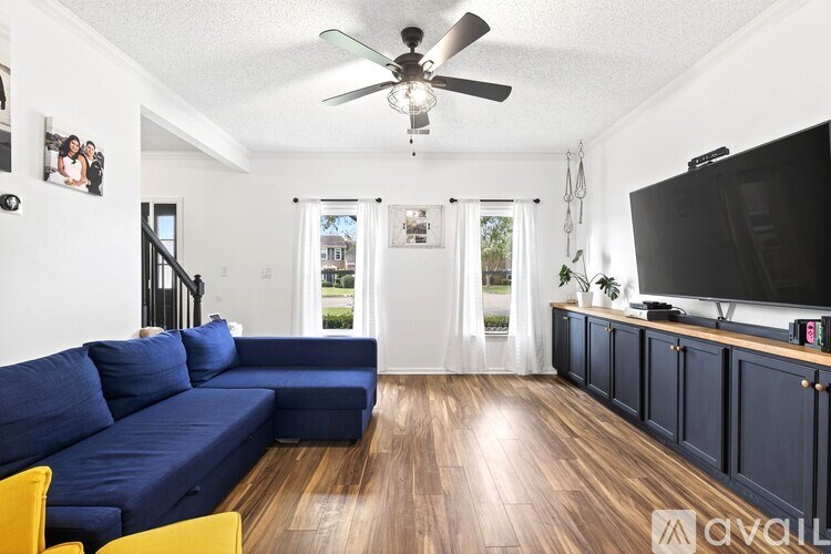 A living room with a blue couch and a ceiling fan.