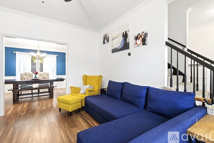 A living room with a blue couch, yellow chair, and pictures on the wall.
