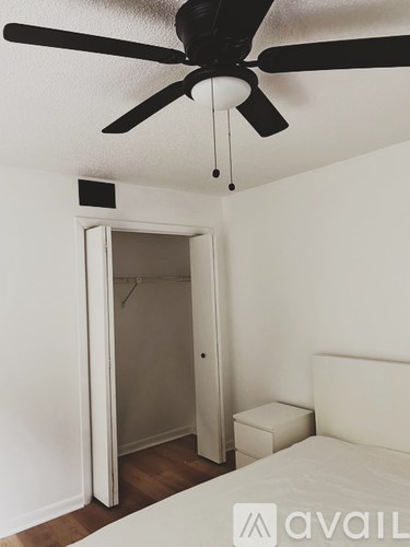 A bedroom with a bed, a ceiling fan, and a closet.