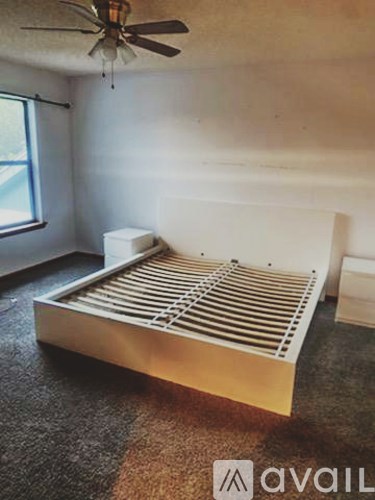 A bed with a metal frame is in a room with a ceiling fan.