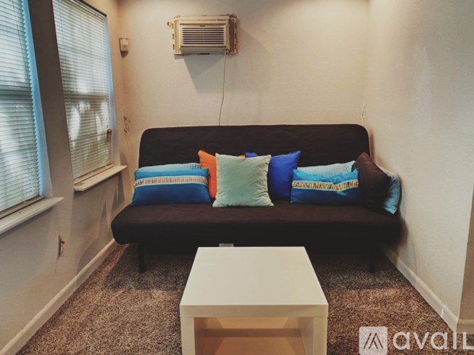 A living room with a black couch and a white coffee table.