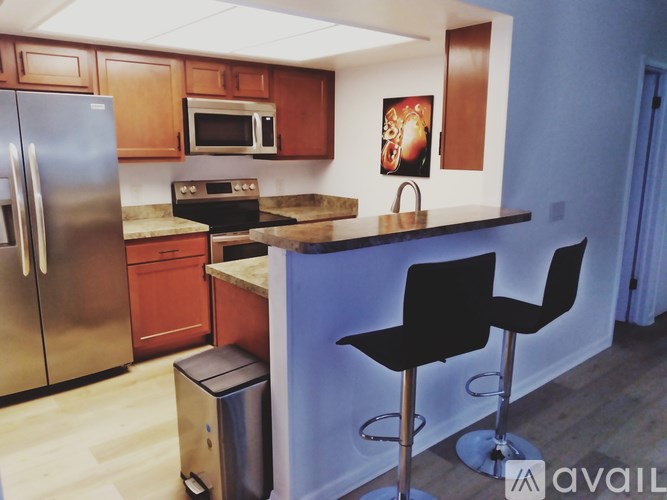 A kitchen with a bar stool and a fridge.