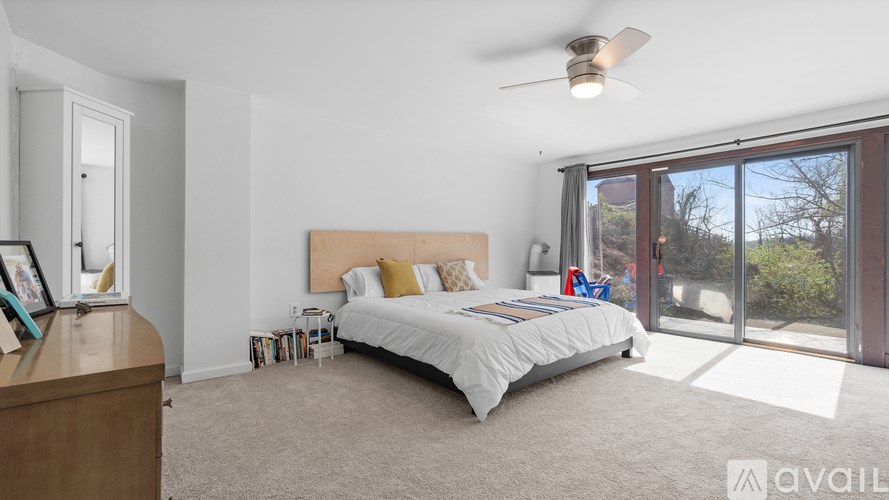 A bedroom with a large bed and a sliding glass door leading to a balcony.